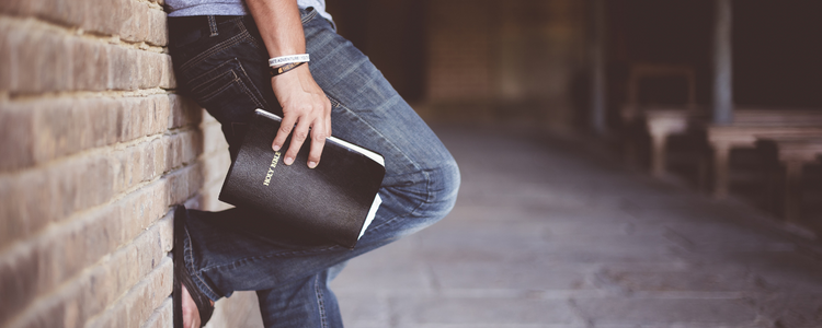 Man Leaning Against Wall With Bible