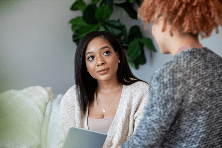 Woman of color sitting talking to female therapist