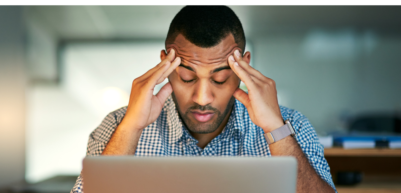A man sitting in front of a laptop with his head in his hands.