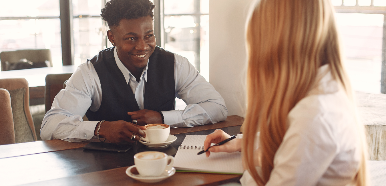 A man and woman having coffee together at a table.