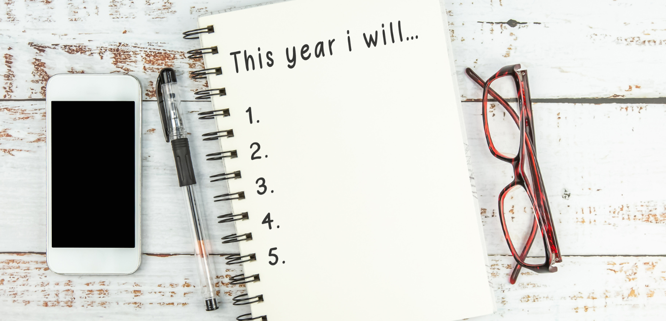 A spiral notebook laying on a table with a list of things to do this year.